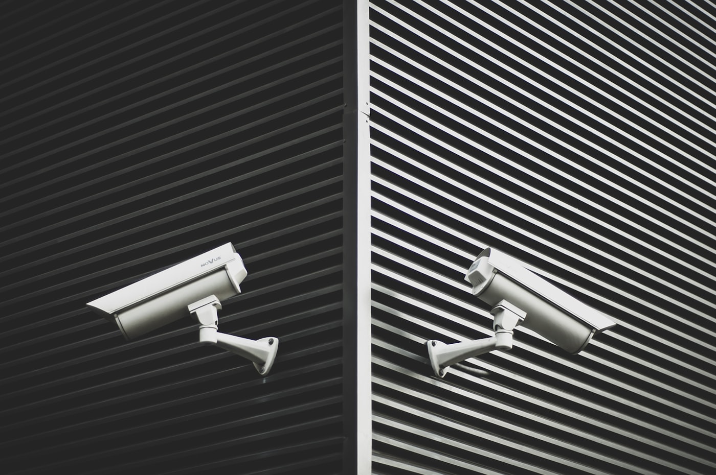 Two surveillance cameras mounted on a striped building facade
